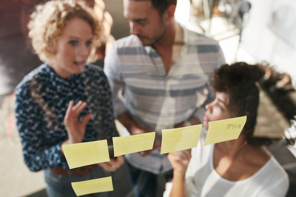 3-mistakes-to-avoid-in-story-maps People in a meeting looking at sticky notes through glass