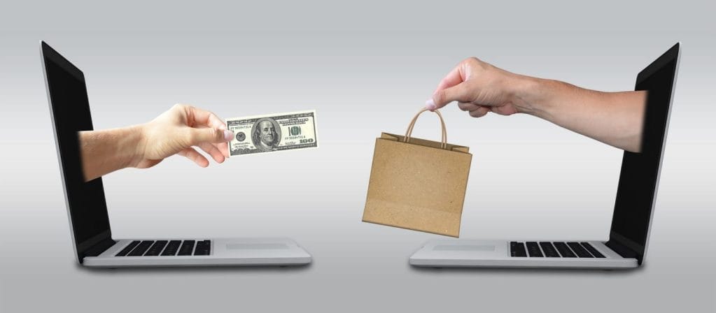 ecommerce-2140604_1920 Person handing another person a bag and money through 2 computer screens